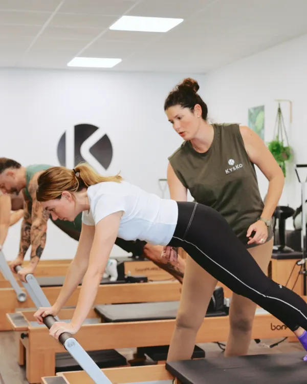 Une formatrice corrige une élève sur un Reformer à la Kysko Academy